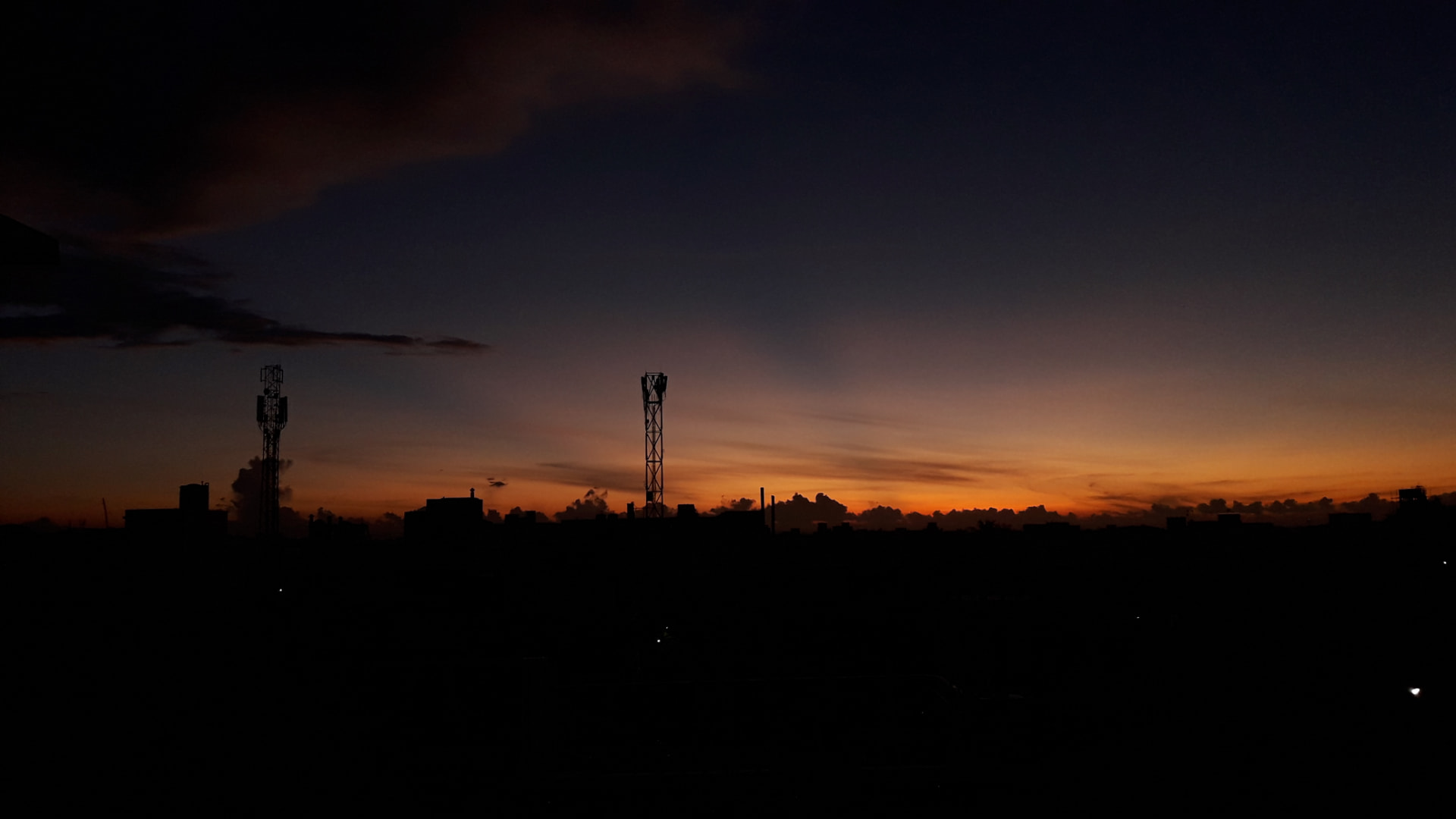 Dark urban skyline silhouetted against a deep orange sunset