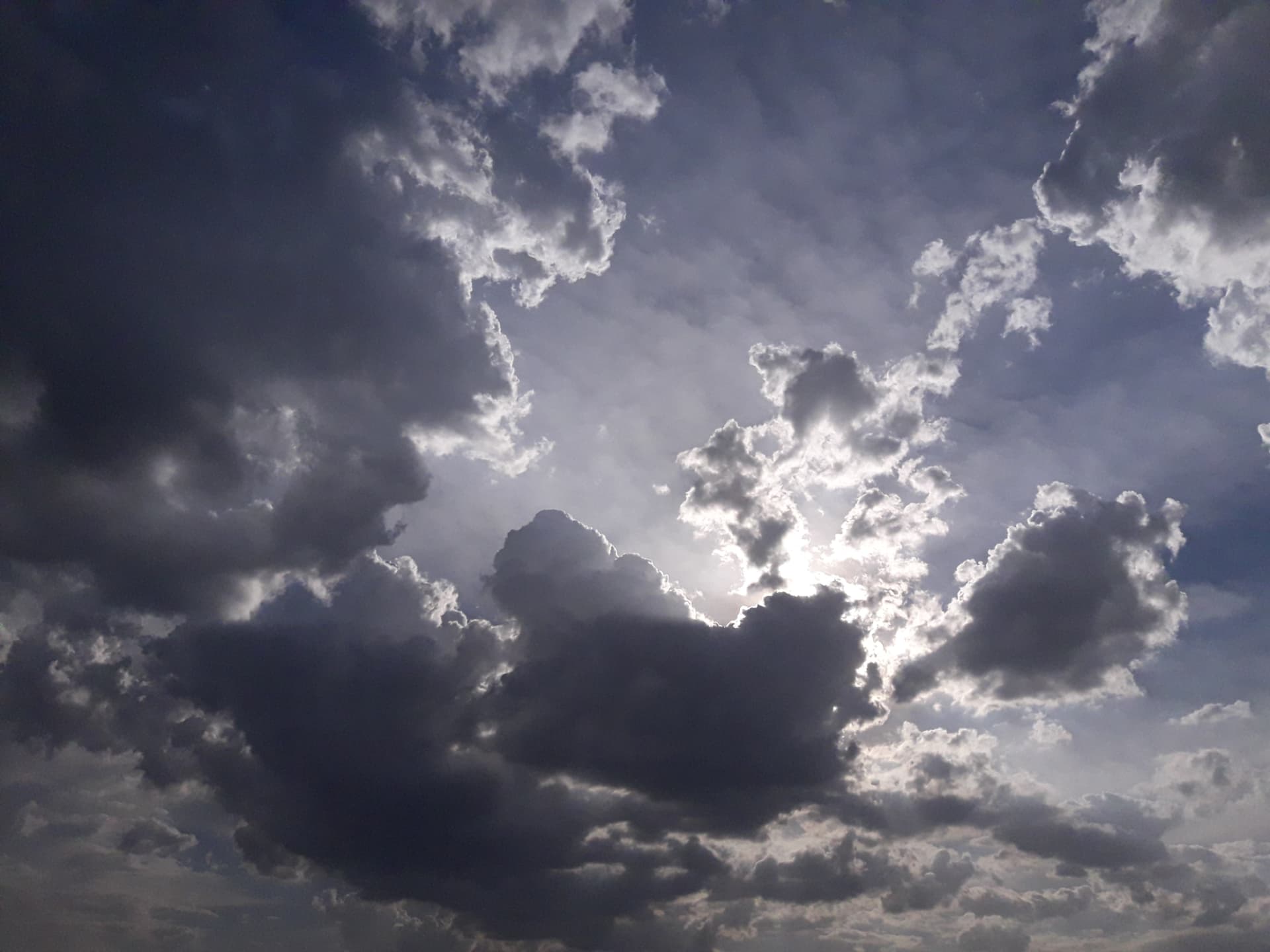 Sunlight breaking through layered dark clouds in a dramatic sky