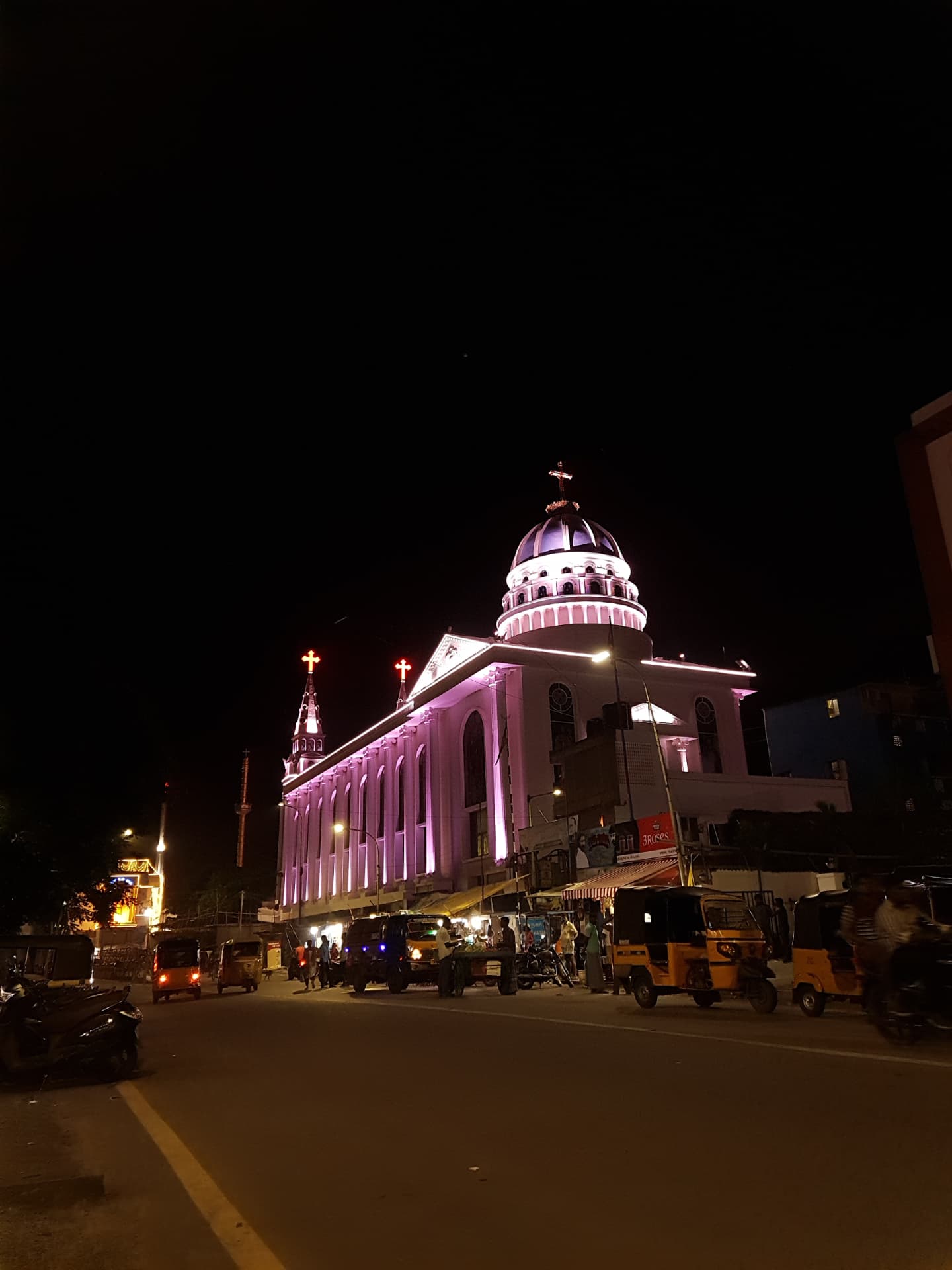 Besant Nagar church illuminated at night above a busy street