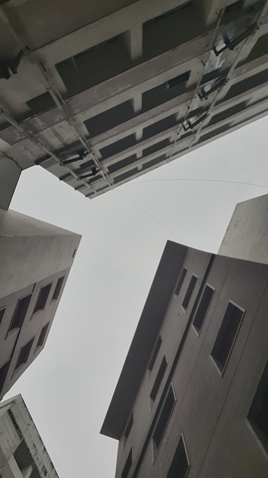 Upward view framed by tall concrete buildings and an exposed overhead structure